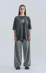 Remera negra con efecto nevado, cuello redondo y calce oversize. Estampado frontal de Mickey Mouse con una patineta.
