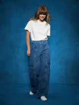 Pantalón de jean de tiro alto, color azul medio, con corte ancho y pierna recta. Presenta costuras marcadas en el centro de las piernas y bolsillos cargo a los lados.