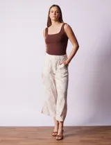 Pantalón crop de lino estampado con hojas en tonos verdes y azules. Tiene pretina trasera elastizada y bolsillos delanteros.