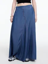 Falda larga de denim liviano color azul, confeccionada en 100% lyocell. Tiene silueta amplia y fluida, cintura con elástico en la parte trasera, bolsillos laterales y recorte delantero con costuras a contratono.