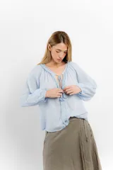 Blusa rosa de algodón con escote en V con cordones y detalle de volados.