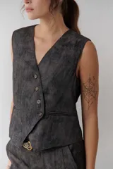 Chaleco grafito con cuello en V, cierre frontal con botones y bolsillos ribeteados.