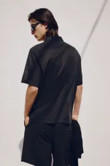 Camisa negra de manga corta en mezcla de algodón y lino. Modelo con cuello abierto, tapeta lisa y bolsillo superior abierto.