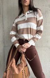 Buzo de tejido de punto color beige con rayas horizontales blancas, cuello polo con botones y mangas largas.
