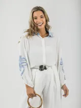 Camisa blanca de tela fresca con cuello camisero celeste y mangas abullonadas con apliques en denim celeste.