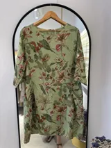 Vestido midi verde con estampado floral, confeccionado en lino italiano, con escote redondo y mangas tres cuartos con botón ajustable.