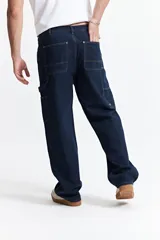 Pantalón jean celeste de corte carpenter, tiro medio, con presillas para cinturón y bolsillos laterales.