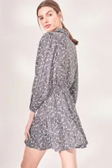 Vestido corto con estampado floral en blanco y negro, cuello camisero, mangas largas abullonadas y falda evasé con detalle de borlas.