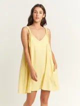 Vestido amarillo con tirantes ajustables, largo por encima de la rodilla y bolsillos laterales.