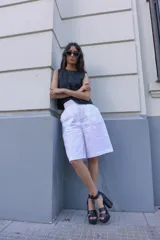 Bermuda blanca de lino, corte sastre, tiro alto, largo a la rodilla y bolsillos laterales.