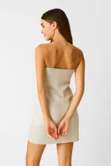 Vestido corto strapless color beige con textura brillante y corte ajustado al cuerpo.