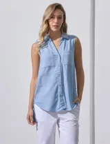 Camisa sin mangas color celeste, confeccionada en lino. Presenta cuello camisero, escote en V, abertura frontal con botones, dos bolsillos de parche en el pecho y terminación con botones en los laterales.