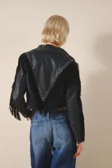 Campera corta de cuero color negro, con flecos en espalda y mangas, tachas metálicas y símil piedra cristal. Cierra con broches en el frente, tiene forrería y bolsillo interno.