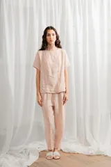 Blusa blanca de lino, corte holgado, con cuello redondo y cierre frontal con botones.