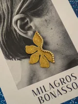 Par de aros con forma de flor roja brillante y detalle de strass plateado en el centro. Cierre a presión de acero inoxidable.