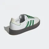 Championes Adidas Sambae blancos con detalles en verde, cordones verdes y suela de goma marrón traslúcida.