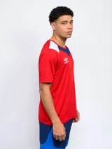 Remera de fútbol Umbro del Club Nacional de Football, modelo de entrenamiento. Diseño azul con detalles en blanco y rojo en cuello y mangas. Incluye logo de Umbro y escudo del club en el frente.