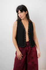 Chaleco negro de tela símil gamuza con terminación de tachas metálicas.