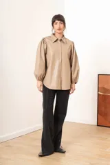Camisa beige de efecto piel con cuello clásico, mangas largas abullonadas y cierre frontal con botones a tono.