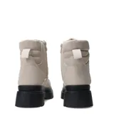 Botas de mujer color beige claro, estilo trekking o montañismo, con caña media y forro interior de borrego o sherpa. Presentan suela track gruesa y dentada de color negro, y sistema de ajuste con cordones y ganchos metálicos.