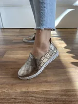 Zapatilla estilo alpargata de cuero color dorado con diseño texturizado tipo piel de cocodrilo y suela blanca.