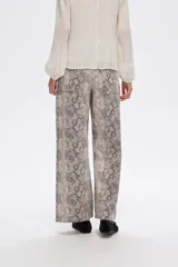 Pantalón jean ancho con estampado de piel de serpiente en tonos beige y gris.