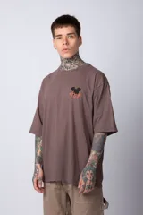 Remera blanca de algodón de corte oversize con mangas cortas y cuello redondo. Presenta un pequeño estampado en el frente con la figura de Mickey Mouse y caracteres orientales.