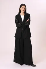 Blazer negro con solapas de muesca, cierre frontal con un botón, mangas largas con detalles de encaje y apliques de perlas sintéticas.