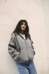 Campera gris con cierre frontal, capucha con cordones ajustables, bolsillos tipo canguro y puños y cintura acanalados.