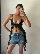 Top negro de lentejuelas con breteles finos y lazo ajustable en el centro del busto.