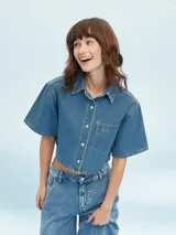 Camisa de denim celeste con corte cropped, mangas cortas y bolsillo en el pecho.