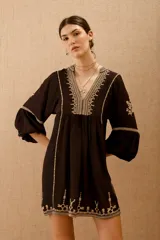 Vestido corto negro con bordado de hilo blanco, escote en V y mangas largas abullonadas.