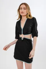 Vestido negro con escote en V, mangas cortas y detalle de argolla en la cintura, terminado con vivos en contraste.