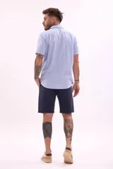 Camisa blanca de manga corta con cuello clásico y cierre frontal con botones.