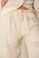Pantalón ancho color crema con bordados florales, 100% algodón, cintura con elástico y detalle en crochet en la cintura.