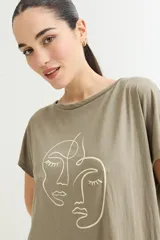 Vestido corto color verde oliva con estampado de dos rostros en color blanco.