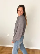 Sweater de tejido calado color gris, con cuello redondo y mangas globo.