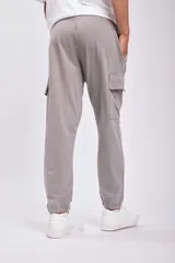 Pantalón deportivo tipo jogger color gris con bolsillos cargo laterales y tobillos ajustados.