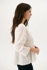 Camisa blanca con bordado floral, cuello en V y cierre frontal con botones.