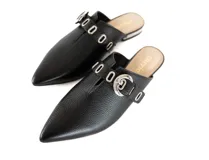 Mulas negras de cuero texturizado con punta afilada, abertura central, tira con hebilla plateada y mini taco metalizado plateado.