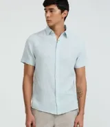 Camisa de hombre de corte regular, confeccionada en una mezcla de lino y algodón. Presenta cuello inglés, manga corta y cierre frontal con botones. Diseño liso en color celeste claro.