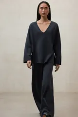 Sweater de tejido de punto color gris oscuro, con escote en V profundo y mangas largas amplias. El diseño es holgado y presenta aberturas laterales.