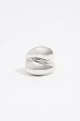 Anillo plateado de metal con diseño en espiral y logo grabado.