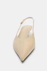 Zapato destalonado tipo slingback color beige, con punta fina, tacón kitten fino y tira trasera ajustable con hebilla metálica.