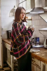 Sweater de lana tejido a mano con diseño geométrico multicolor sobre fondo negro, de calce holgado, cuello redondo y puños ajustados.