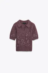 Jersey de punto color borgoña con cuello solapa y escote en pico. Tiene mangas cortas y bordados florales a tono.