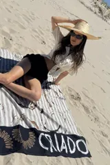 Pareo negro con estampado de rayas verticales en tonos grises y diseño abstracto en la parte inferior.