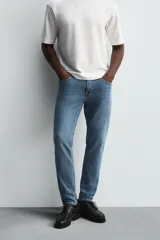 Pantalón de jean negro, corte slim fit, con tiro medio, cinco bolsillos, efecto lavado y cierre frontal con cremallera y botón.