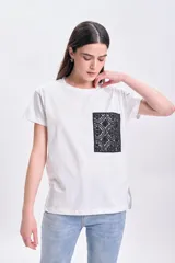Remera blanca de algodón de corte recto, con cuello redondo y mangas cortas. Presenta un bolsillo de encaje negro en el pecho.