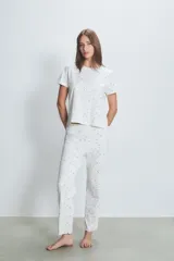 Conjunto de pijama blanco con estampado de lunares negros, compuesto por una remera de manga corta y un pantalón largo.